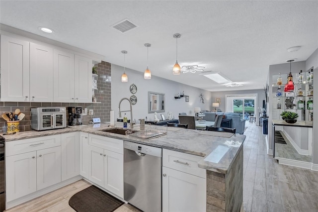 900 Maclaren Dr N Unit D, Palm Harbor, FL 34684 - kitchen featuring dishwasher, a peninsula, open floor plan, light wood-type flooring, and a textured ceiling