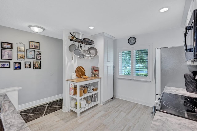 900 Maclaren Dr N Unit D, Palm Harbor, FL 34684 - kitchen featuring light wood finished floors, range with electric cooktop, black microwave, recessed lighting, and white cabinets