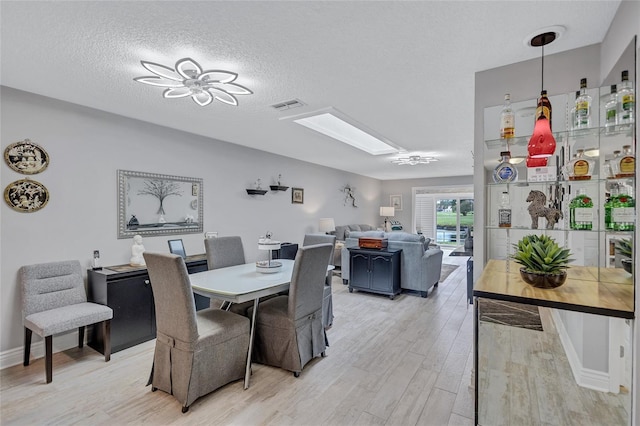 900 Maclaren Dr N Unit D, Palm Harbor, FL 34684 - dining space featuring a skylight, light wood finished floors, and a textured ceiling