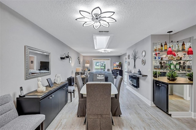 900 Maclaren Dr N Unit D, Palm Harbor, FL 34684 - dining area featuring light wood-style floors, a textured ceiling, a ceiling fan, and bar