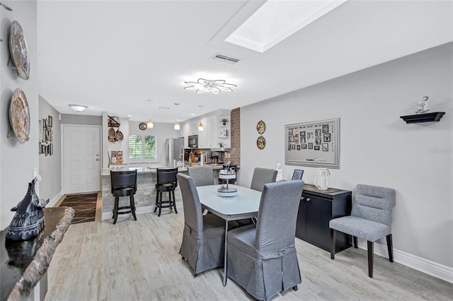 900 Maclaren Dr N Unit D, Palm Harbor, FL 34684 - dining room featuring light wood-style flooring and a skylight