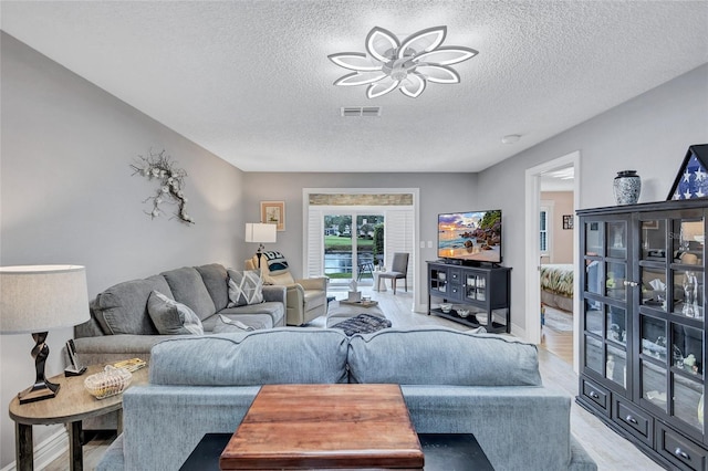 900 Maclaren Dr N Unit D, Palm Harbor, FL 34684 - living room featuring a textured ceiling, light wood-type flooring, and a ceiling fan