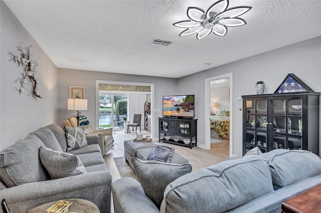 900 Maclaren Dr N Unit D, Palm Harbor, FL 34684 - living area with ceiling fan, light wood finished floors, and a textured ceiling