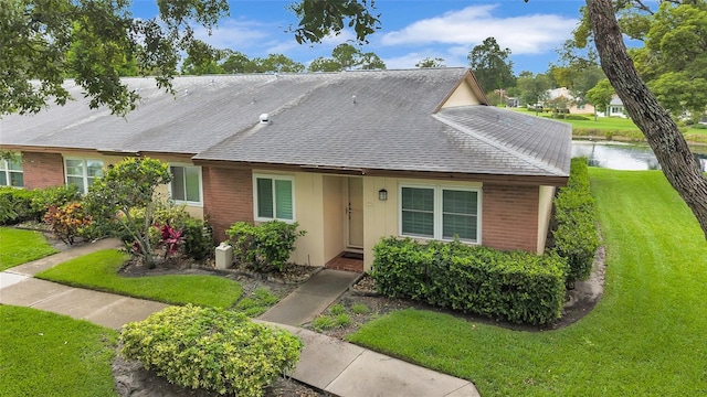 900 Maclaren Dr N Unit D, Palm Harbor, FL 34684 - view of front of property with a front yard, a water view, a shingled roof, and brick siding