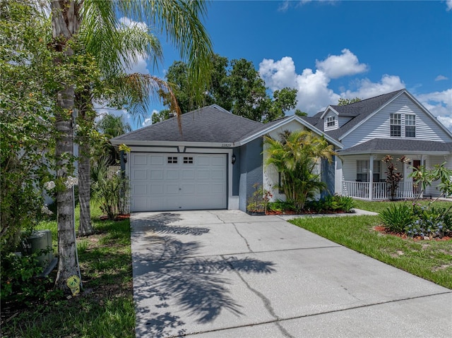 22829 Saint Thomas Cir, Lutz, FL 33549 - view of front of house with driveway, a garage, covered porch, and roof with shingles