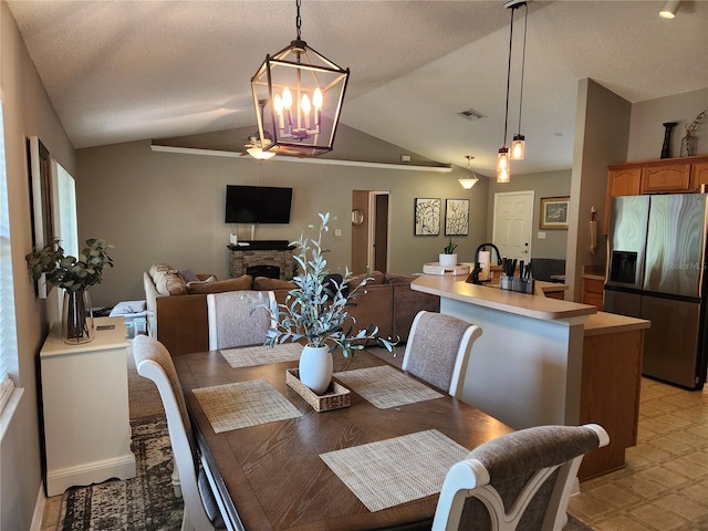 2509 Montecito Ave, Eustis, FL 32726 - dining room with lofted ceiling, a stone fireplace, a chandelier, a ceiling fan, and a textured ceiling