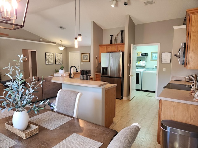 2509 Montecito Ave, Eustis, FL 32726 - kitchen featuring appliances with stainless steel finishes, washer and clothes dryer, lofted ceiling, light countertops, and light floors