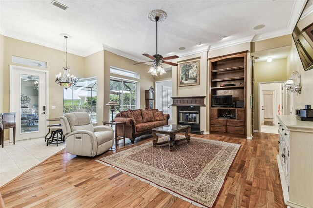 17906 Loretta Ln, Lutz, FL 33548 - living area featuring ceiling fan, a glass covered fireplace, light wood-style floors, ornamental molding, and a textured ceiling