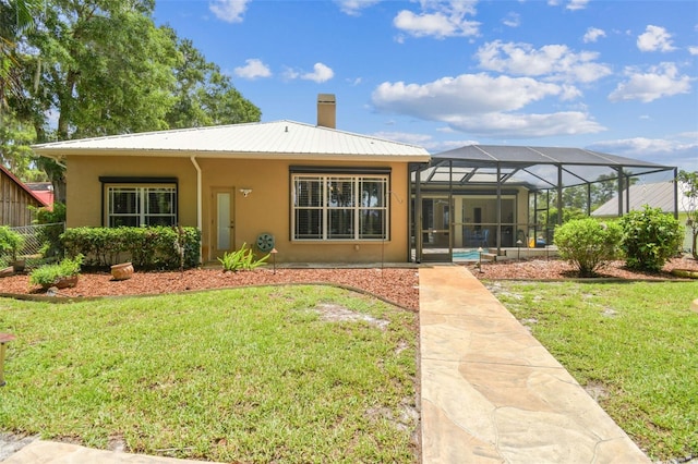 17906 Loretta Ln, Lutz, FL 33548 - rear view of property featuring stucco siding, a yard, glass enclosure, a metal roof, and a chimney
