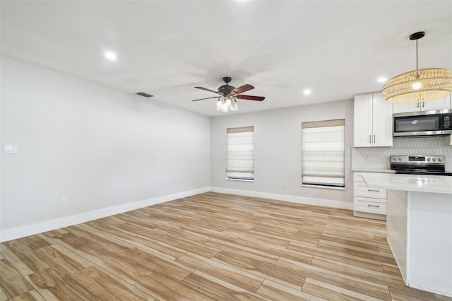 206 N Beverly Ave Unit 1/2, Tampa, FL 33609 - kitchen featuring stainless steel appliances, light countertops, decorative backsplash, a ceiling fan, and light wood finished floors