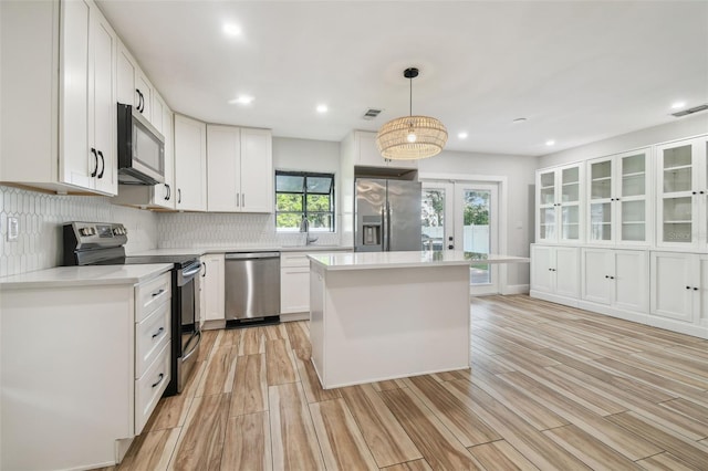 206 N Beverly Ave Unit 1/2, Tampa, FL 33609 - kitchen featuring appliances with stainless steel finishes, decorative backsplash, white cabinets, light countertops, and a center island