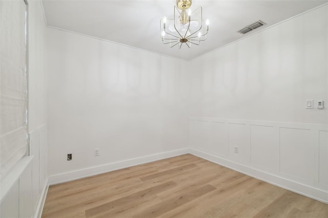 206 N Beverly Ave Unit 1/2, Tampa, FL 33609 - unfurnished room with a chandelier, light wood-style flooring, a wainscoted wall, and a decorative wall