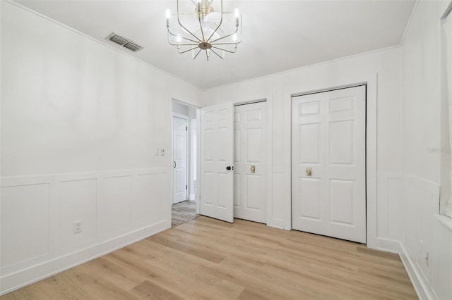 206 N Beverly Ave Unit 1/2, Tampa, FL 33609 - unfurnished bedroom with a decorative wall, a chandelier, light wood-style floors, multiple closets, and ornamental molding