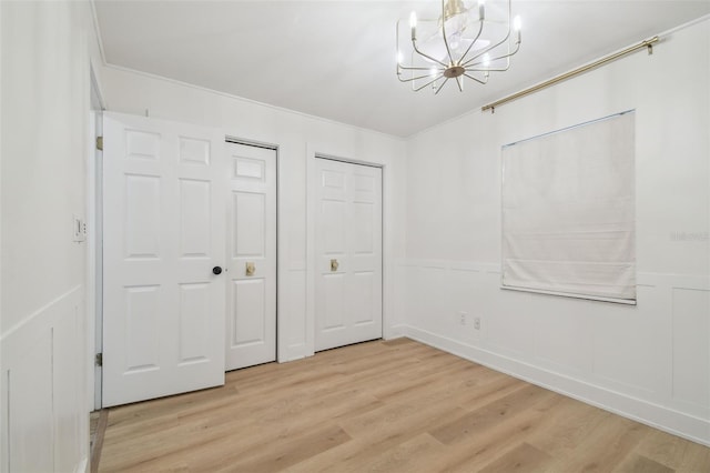 206 N Beverly Ave Unit 1/2, Tampa, FL 33609 - unfurnished bedroom with a chandelier, light wood-style floors, multiple closets, wainscoting, and a decorative wall