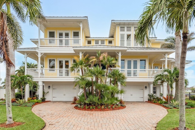 442 Midway Is, Clearwater Beach, FL 33767 - coastal inspired home featuring a balcony, a standing seam roof, decorative driveway, french doors, and an attached garage
