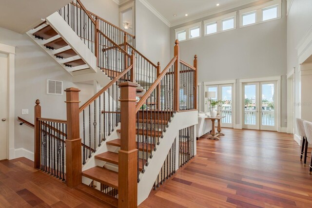 442 Midway Is, Clearwater Beach, FL 33767 - stairway featuring wood finished floors, plenty of natural light, a towering ceiling, french doors, and crown molding