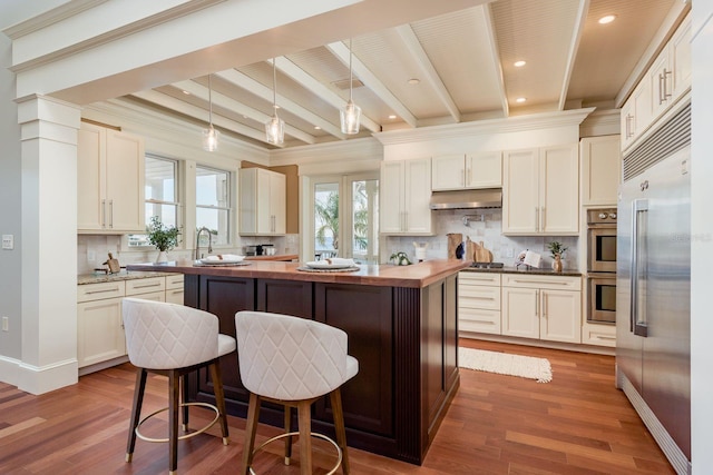 442 Midway Is, Clearwater Beach, FL 33767 - kitchen with stainless steel appliances, under cabinet range hood, a kitchen island, beam ceiling, and decorative backsplash