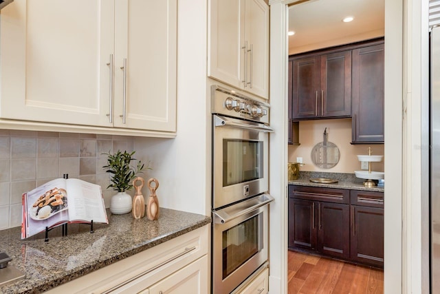 442 Midway Is, Clearwater Beach, FL 33767 - kitchen with double oven, dark brown cabinets, dark stone countertops, backsplash, and recessed lighting