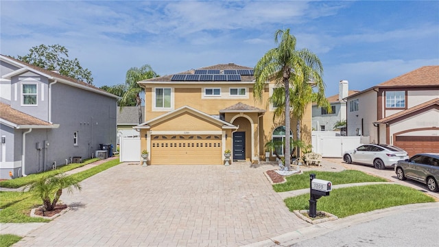 1205 Sweet Gum Dr, Brandon, FL 33511 - view of front of house featuring decorative driveway, solar panels, stucco siding, an attached garage, and a gate