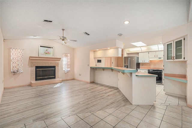4355 Odin St, Spring Hill, FL 34608 - kitchen featuring stove, stainless steel refrigerator with ice dispenser, a peninsula, light tile patterned floors, and under cabinet range hood