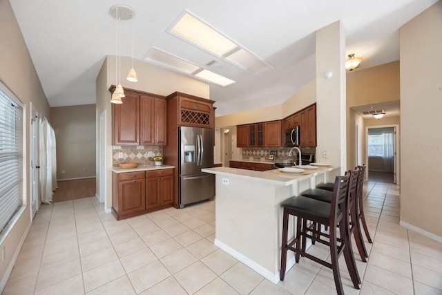 12405 Pathway Ct, Riverview, FL 33569 - kitchen featuring appliances with stainless steel finishes, tasteful backsplash, a peninsula, a breakfast bar area, and light tile patterned floors