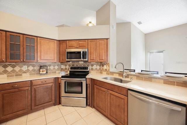 12405 Pathway Ct, Riverview, FL 33569 - kitchen with appliances with stainless steel finishes, brown cabinetry, decorative backsplash, and light tile patterned floors