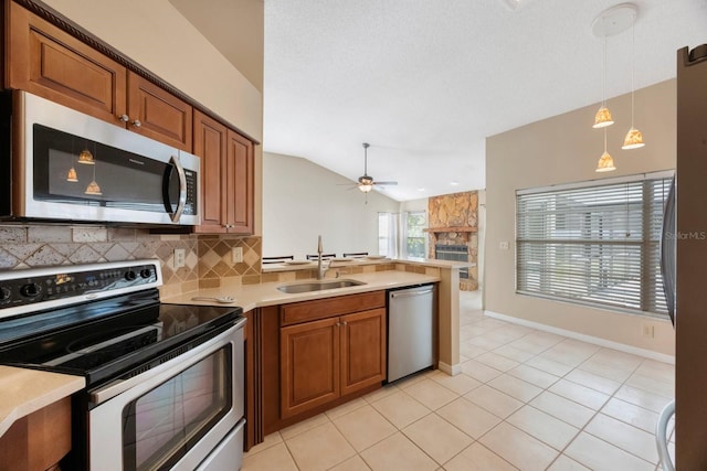12405 Pathway Ct, Riverview, FL 33569 - kitchen featuring appliances with stainless steel finishes, a peninsula, brown cabinets, decorative backsplash, and lofted ceiling