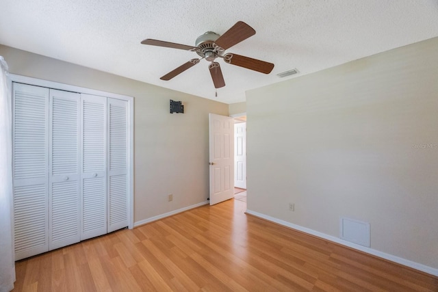 12405 Pathway Ct, Riverview, FL 33569 - unfurnished bedroom featuring light wood-style floors, a closet, a textured ceiling, and ceiling fan