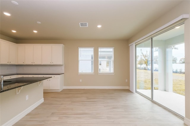 5909 Bibb Ct, North Port, FL 34288 - kitchen with light wood-type flooring, healthy amount of natural light, white cabinets, dark stone countertops, and recessed lighting