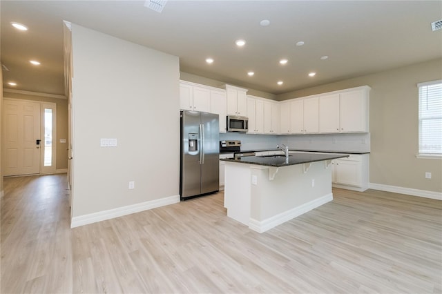 5909 Bibb Ct, North Port, FL 34288 - kitchen featuring appliances with stainless steel finishes, a kitchen breakfast bar, light wood-style flooring, a center island with sink, and white cabinets