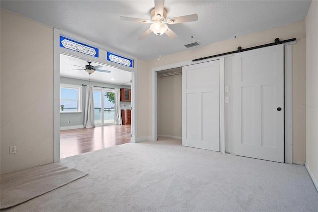 17 Freshwater Dr, Palm Harbor, FL 34684 - unfurnished bedroom with light colored carpet, a barn door, ceiling fan, and a closet