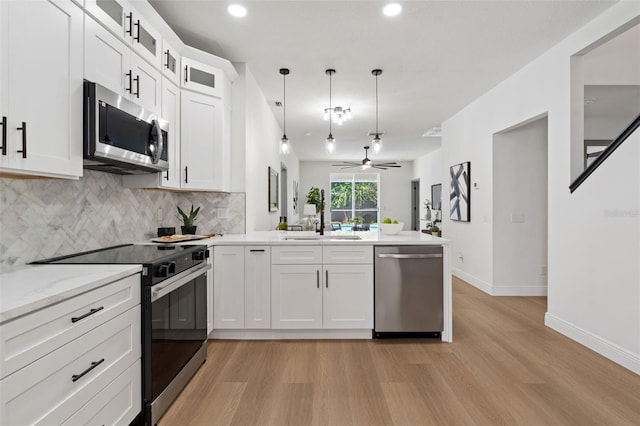 1800 Loch Haven Ct, Trinity, FL 34655 - kitchen with stainless steel appliances, a peninsula, light wood-style floors, backsplash, and open floor plan