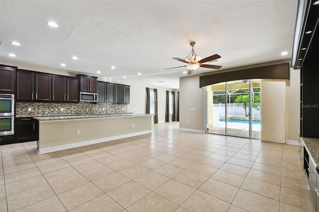 4544 Vermillion Sky Dr, Wesley Chapel, FL 33544 - kitchen with stainless steel appliances, ceiling fan, open floor plan, decorative backsplash, and a textured ceiling
