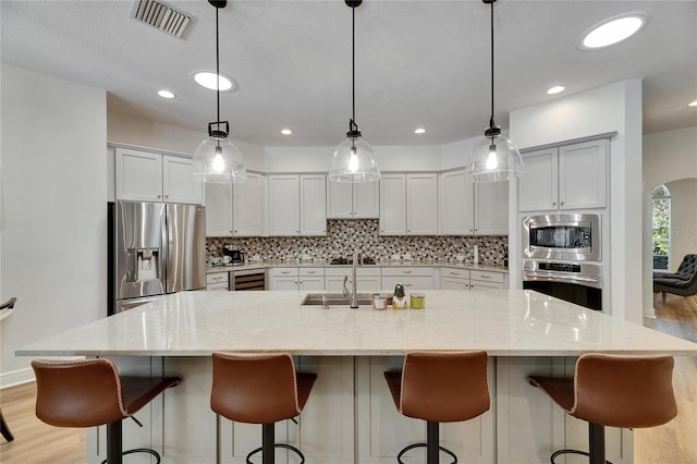5804 Terncrest Dr, Lithia, FL 33547 - kitchen with appliances with stainless steel finishes, backsplash, light wood-type flooring, wine cooler, and recessed lighting