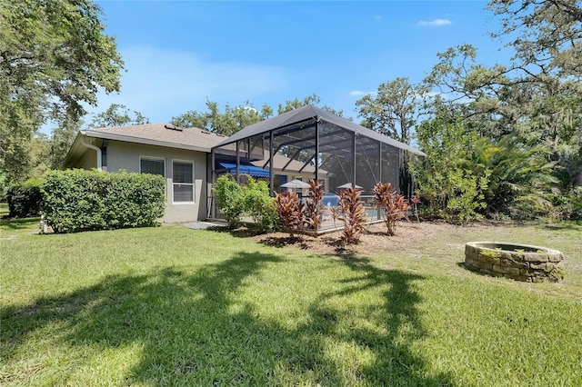 5804 Terncrest Dr, Lithia, FL 33547 - back of house featuring stucco siding, a fire pit, a yard, and glass enclosure