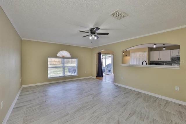 11438 Ivy Flower Loop, Riverview, FL 33578 - unfurnished living room with arched walkways, ceiling fan, ornamental molding, and a textured ceiling