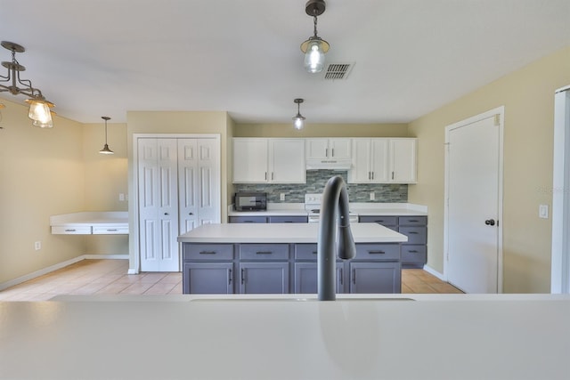 11438 Ivy Flower Loop, Riverview, FL 33578 - kitchen featuring light tile patterned floors, backsplash, under cabinet range hood, pendant lighting, and light countertops
