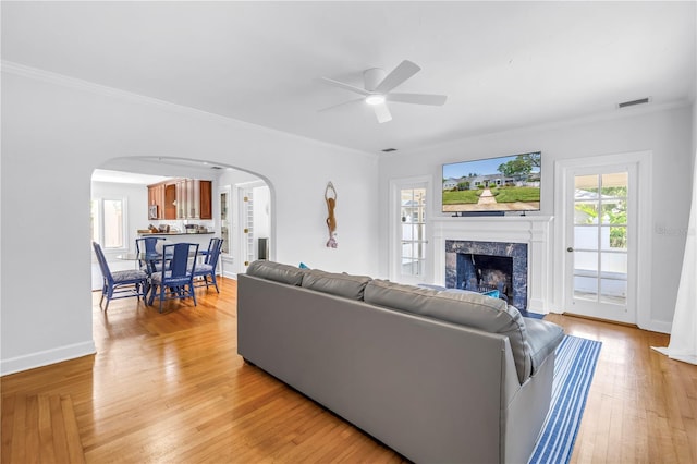 555 21st Ave NE, Saint Petersburg, FL 33704 - living room featuring arched walkways, a ceiling fan, a fireplace, light wood-style floors, and ornamental molding