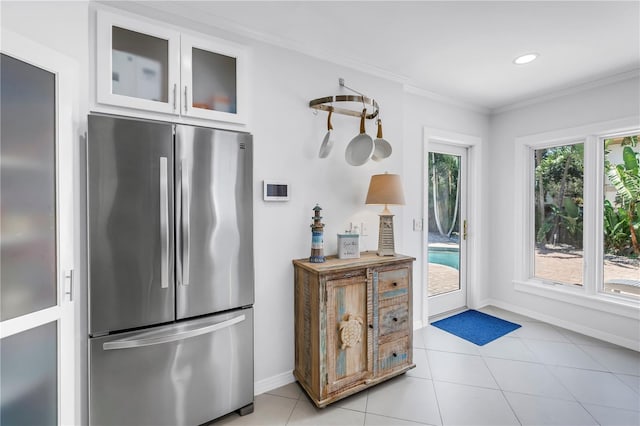 555 21st Ave NE, Saint Petersburg, FL 33704 - kitchen featuring freestanding refrigerator, ornamental molding, white cabinetry, light tile patterned floors, and glass insert cabinets