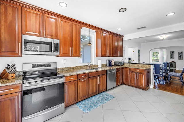 555 21st Ave NE, Saint Petersburg, FL 33704 - kitchen featuring appliances with stainless steel finishes, a peninsula, light stone countertops, brown cabinets, and recessed lighting