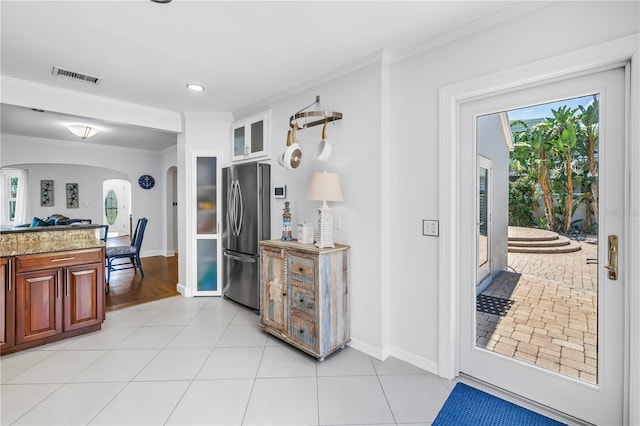 555 21st Ave NE, Saint Petersburg, FL 33704 - kitchen featuring freestanding refrigerator, arched walkways, ornamental molding, glass insert cabinets, and light stone counters