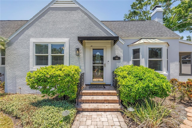555 21st Ave NE, Saint Petersburg, FL 33704 - property entrance featuring stucco siding, roof with shingles, and a chimney
