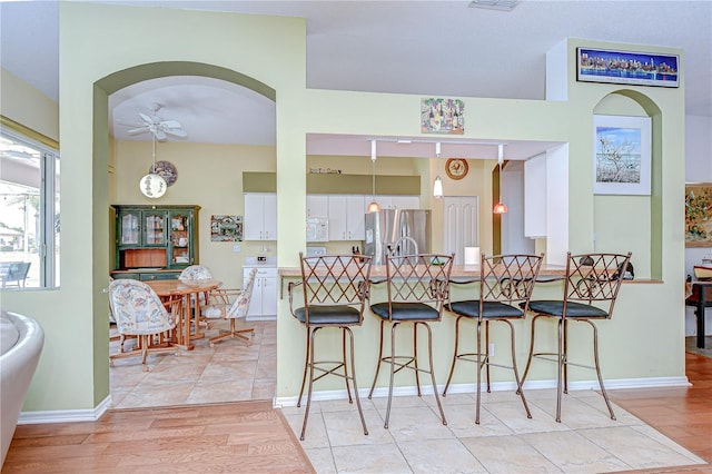 2226 N Creek Ct, Sun City Center, FL 33573 - kitchen featuring stainless steel refrigerator with ice dispenser, a ceiling fan, white cabinetry, a kitchen breakfast bar, and white microwave