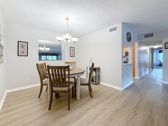 1207 Pine Ridge Cir W Unit H2, Tarpon Springs, FL 34688 - dining space featuring a chandelier, light wood finished floors, and a textured ceiling