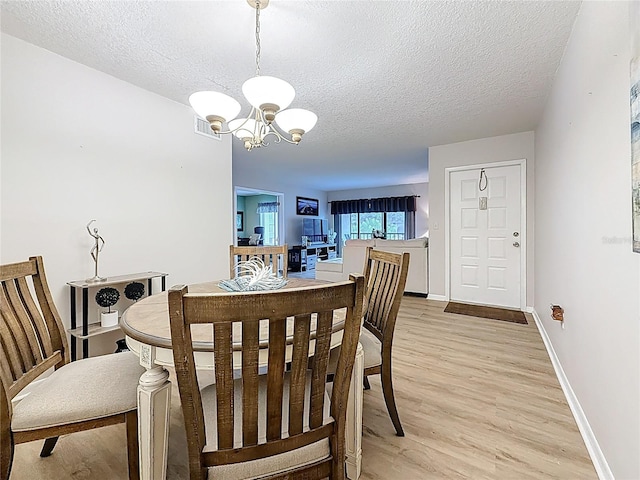 1207 Pine Ridge Cir W Unit H2, Tarpon Springs, FL 34688 - dining space with a chandelier, a textured ceiling, and light wood-type flooring