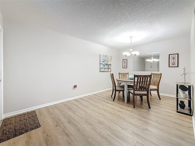 1207 Pine Ridge Cir W Unit H2, Tarpon Springs, FL 34688 - dining room with a chandelier, light wood-type flooring, and a textured ceiling