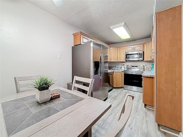 1207 Pine Ridge Cir W Unit H2, Tarpon Springs, FL 34688 - kitchen featuring appliances with stainless steel finishes, light wood-style floors, a textured ceiling, and light countertops