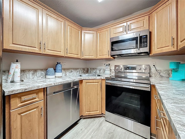 1207 Pine Ridge Cir W Unit H2, Tarpon Springs, FL 34688 - kitchen with appliances with stainless steel finishes, light wood finished floors, light countertops, and light brown cabinets