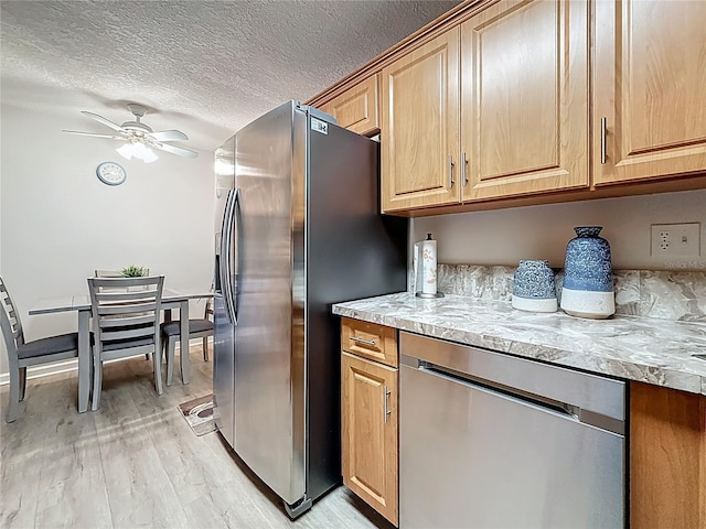 1207 Pine Ridge Cir W Unit H2, Tarpon Springs, FL 34688 - kitchen featuring stainless steel appliances, light wood-style flooring, a ceiling fan, a textured ceiling, and light stone counters