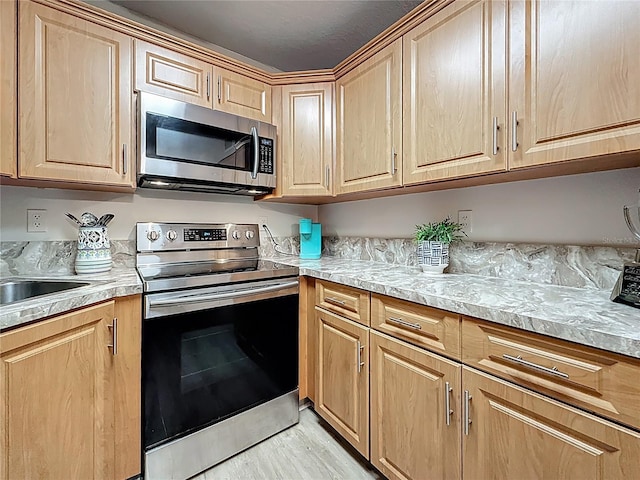 1207 Pine Ridge Cir W Unit H2, Tarpon Springs, FL 34688 - kitchen with stainless steel appliances, light brown cabinetry, light countertops, and light wood-style floors